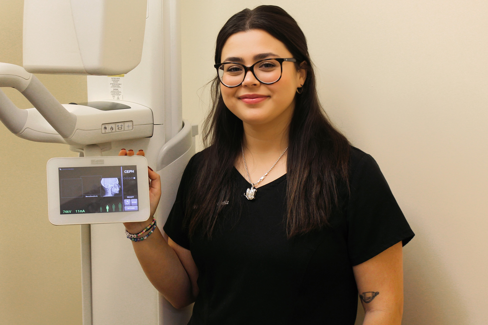 A woman, presumably a healthcare professional, stands in front of a medical imaging machine.