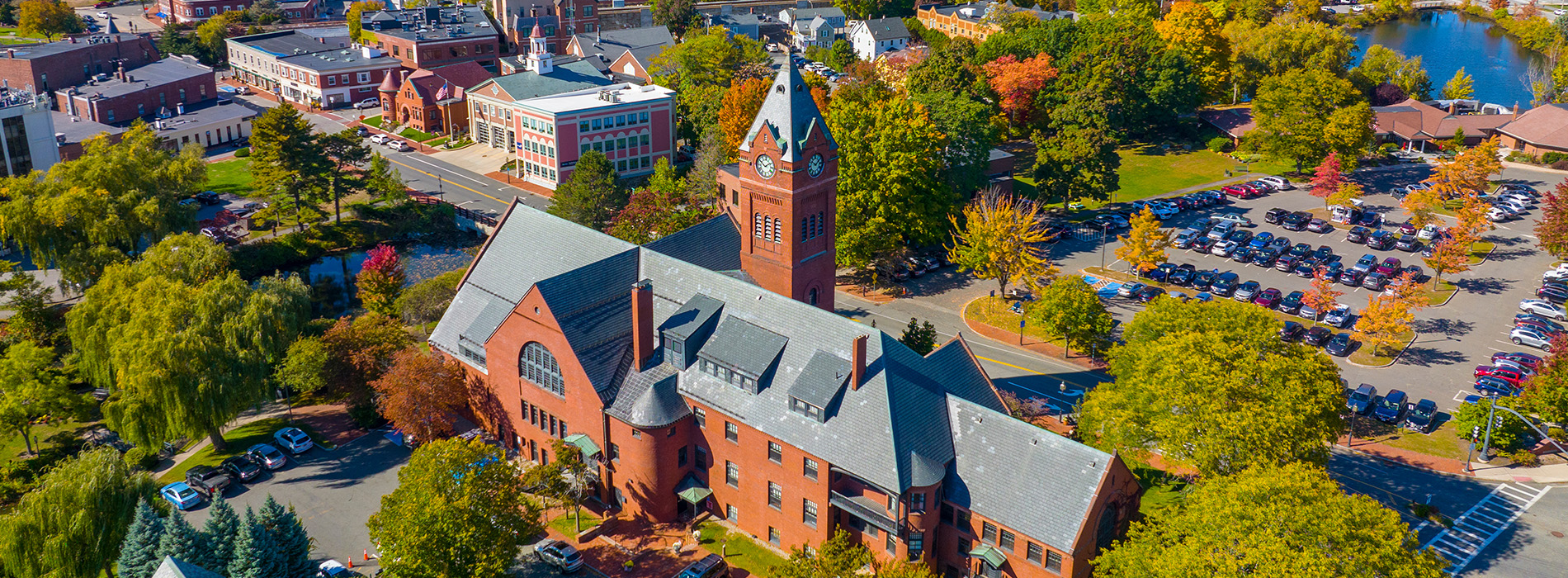 The image shows a large church with a prominent clock tower, set against the backdrop of an autumnal landscape with trees displaying fall colors.