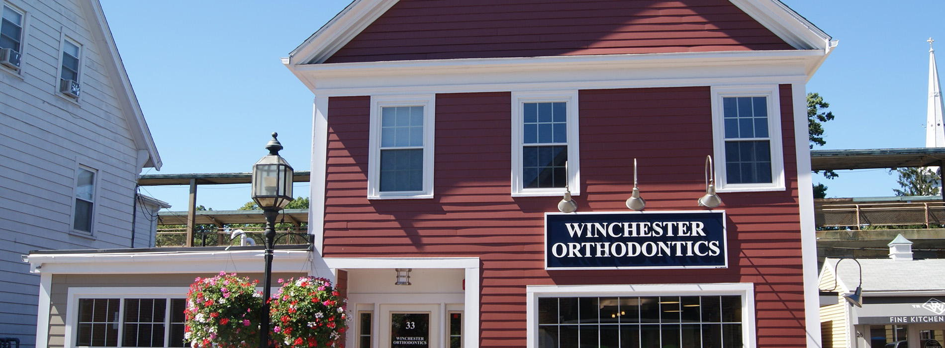 The image shows a red building with white trim, labeled  Winston Orthodontics,  and features a sign that reads  Winston Orthodontics.  It is situated in an outdoor setting, possibly a small town or village.