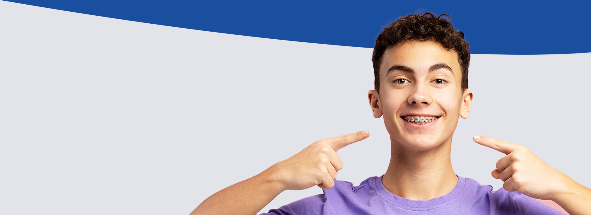 The image shows a young person making a playful gesture with their hand, smiling and pointing at themselves against a plain background.